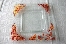 quadratischer Teller mit breitem Rand, dekoriert mit gelben, roten und orangenen Kröseln, gelben Stringern und gemalten Schmetterlingen